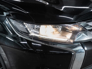 Fototapeta na wymiar Glowing Headlight of a modern car close-up. Car xenon lamp headlight. Exterior of a exprnsive car