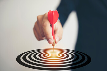 Businessman throwing red arrow dart to  target dart board, business investment concept.