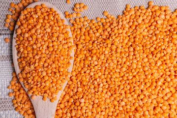 wooden bowl red lentils Lens culinaris against a dark backgroound.