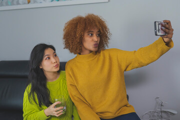 Multiracial friendship. Asian and african american black woman taking selfie using smartphone. High quality photo