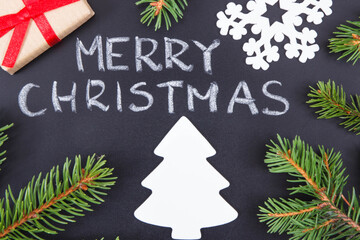 Inscription Merry Christmas, wrapped gift, christmas tree shape and spruce branches. Decoration for christmas time