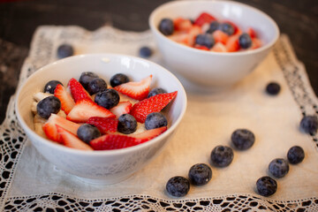 Oatmeal porridge with blueberries and strawberries.Delicious oatmeal with berries in a bowl on the table.