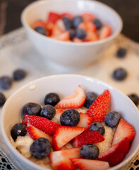 Oatmeal porridge with blueberries and strawberries.Delicious oatmeal with berries in a bowl on the table.