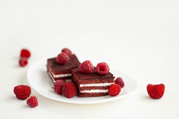 Chocolate-raspberry biscuit decorated with ripe raspberry berries. Sweet berry dessert on a white concrete background.