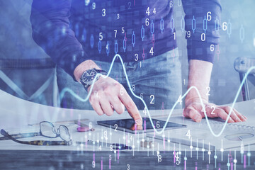 Double exposure of man's hands holding and using a digital device and forex graph drawing. Financial market concept.