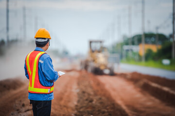 Young Asian engineers supervise road construction and inspect road construction at construction sites.