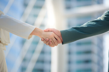 Close-ups of the young business man and the Asian business woman hand in hand. Business people shake hands