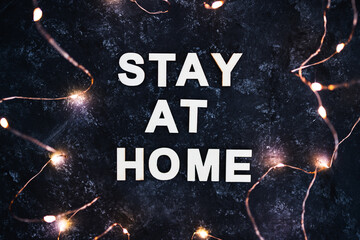 Fototapeta na wymiar holidays in lockdown due to covid, golden fairy lights surrounding message about staying at home