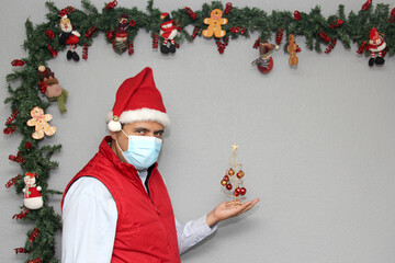 
Latin man with protection mask and Christmas tree with spheres in Christmas decoration, new normal...