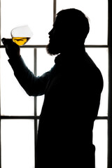 Man's silhouette tasting whisky studio portrait on white background