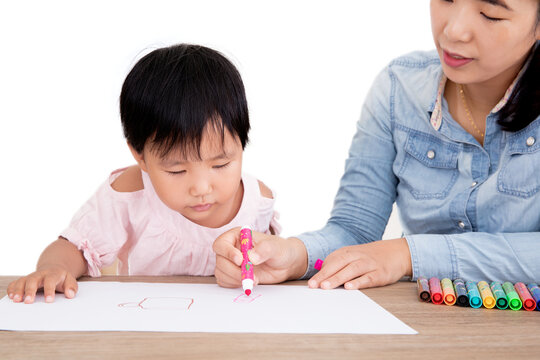 Cute Chinese little girl lying on the table watching mother or teacher drawing