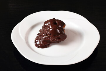 Choux pastry ball with custard filling and chocolate sauce icing