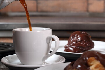 Pouring coffee into cup and profiterole