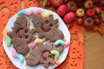 Halloween cookies in shape of a bat filled with marmalade on wooden table. Halloween background 