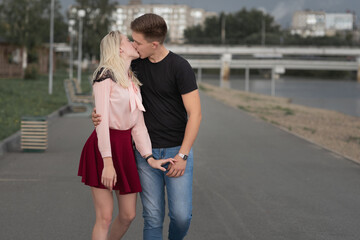 Young couple holding hands and kissing while walking through the street