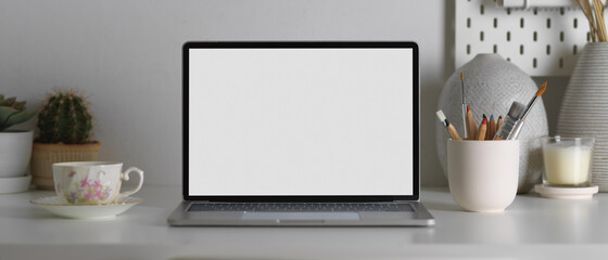 Mock up laptop, stationery and decorations on worktable in home office room, clipping path