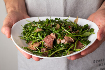 salad with roast beef and arugula in men's hands
