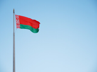 State symbols of the Belarusian flag waving in the wind against a blue sky