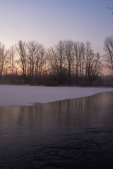Fototapeta premium Breath of winter, first ice on the lake, dawn on a frosty morning with frost on the grass, close-up of frost, patterns on the first ice.