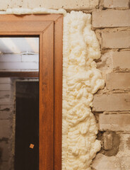 Construction foam between the wall and the door. - obrazy, fototapety, plakaty