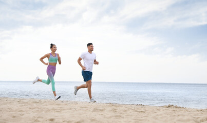 Couple running together on beach, space for text. Body training
