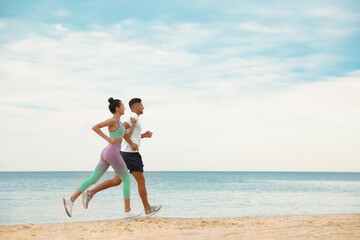 Couple running together on beach, space for text. Body training