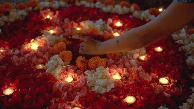 lit a candle in a circle of colorful flowers in the evening