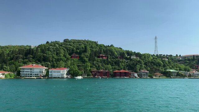 Footage of historical mansions and houses at upscale neighborhoods called "Anadolu Hisari" and "Kandilli"in Istanbul. It is a beautiful Bosphorus scene in a sunny summer day. Camera moves forward.