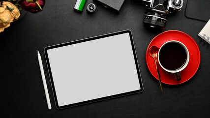 Workspace with tablet, coffee cup, camera and supplies on black table, clipping path