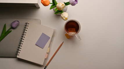 Feminine workspace with notebook, laptop, coffee cup, flower vase and copy space