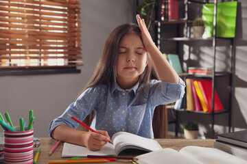 Tired preteen girl at table. Doing homework