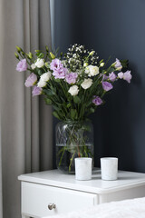 Bouquet of beautiful Eustoma flowers on nightstand in bedroom