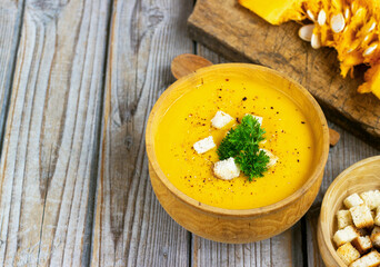 Pumpkin and carrot soup, tadka with cream and parsley on dark wooden background. Top view
