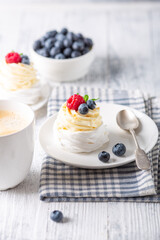 New Zealand Pavlova cake with whipped cream and fresh berries and mug with coffee