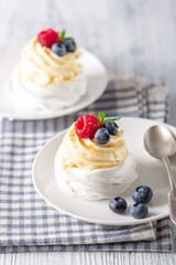 Delicious dessert Pavlova cake with whipped cream and fresh berries on white plate