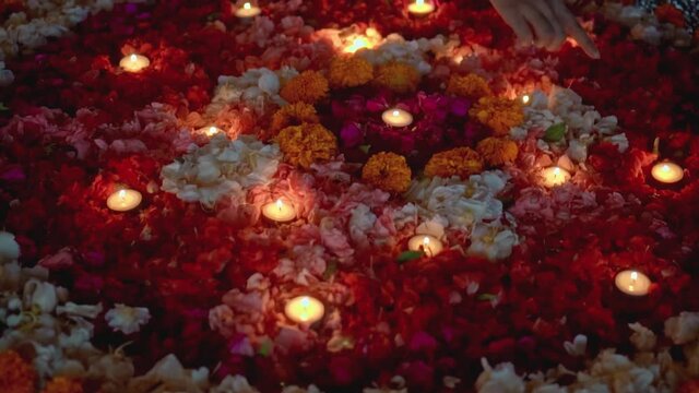 lit a candle in a circle of colorful flowers in the evening