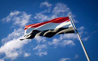 Beautiful national state flag of Yemen fluttering at sky background. Low angle close-up Yemen flag 3D artwork.