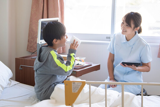 入院中の男の子と女性看護師が仲良く会話をしている