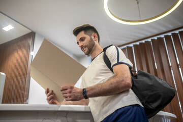 Male customer standing at recepion desk, reading carefully price list
