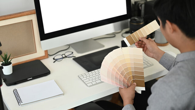 Cropped shot of graphic designer or photographer is working with color palette and choosing color samples for design project at office desk. - Powered by Adobe