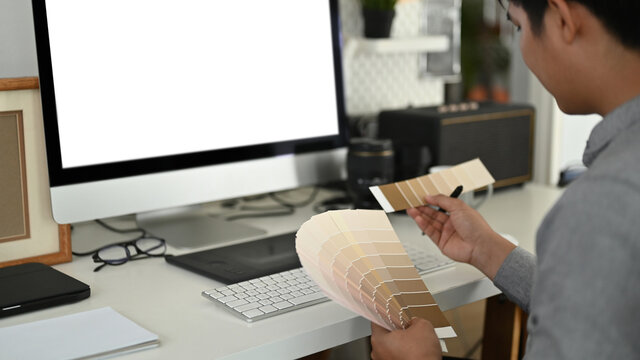 Cropped shot of graphic designer or photographer is choosing color samples for design project at his office.