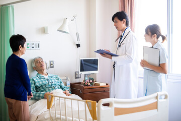 Fototapeta premium 入院中の高齢男性とその妻 回診に来た医師、女性看護師