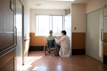 車椅子に乗る高齢患者に寄り添う医師