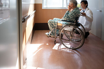 車椅子に乗る高齢患者を励ます医師