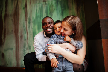 Happy multiethnic family with boy kid spend time at restaurant. Relationships of african man and white european woman.