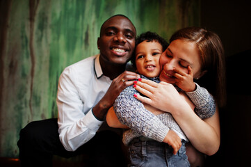 Happy multiethnic family with boy kid spend time at restaurant. Relationships of african man and white european woman.