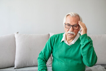 Health care, stress, old age and people concept - Senior man suffering from headache at home. Old...