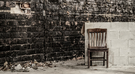 Solitary Wood Chair Set Back Against Paint Chipped Brick Wall. 