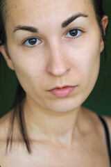 close-up of a young brunette woman looking at the camera on a green background