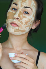 young brunette woman with a clay homemade mask on her face